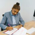 Businesswoman writing plans in a calendar at her office desk.